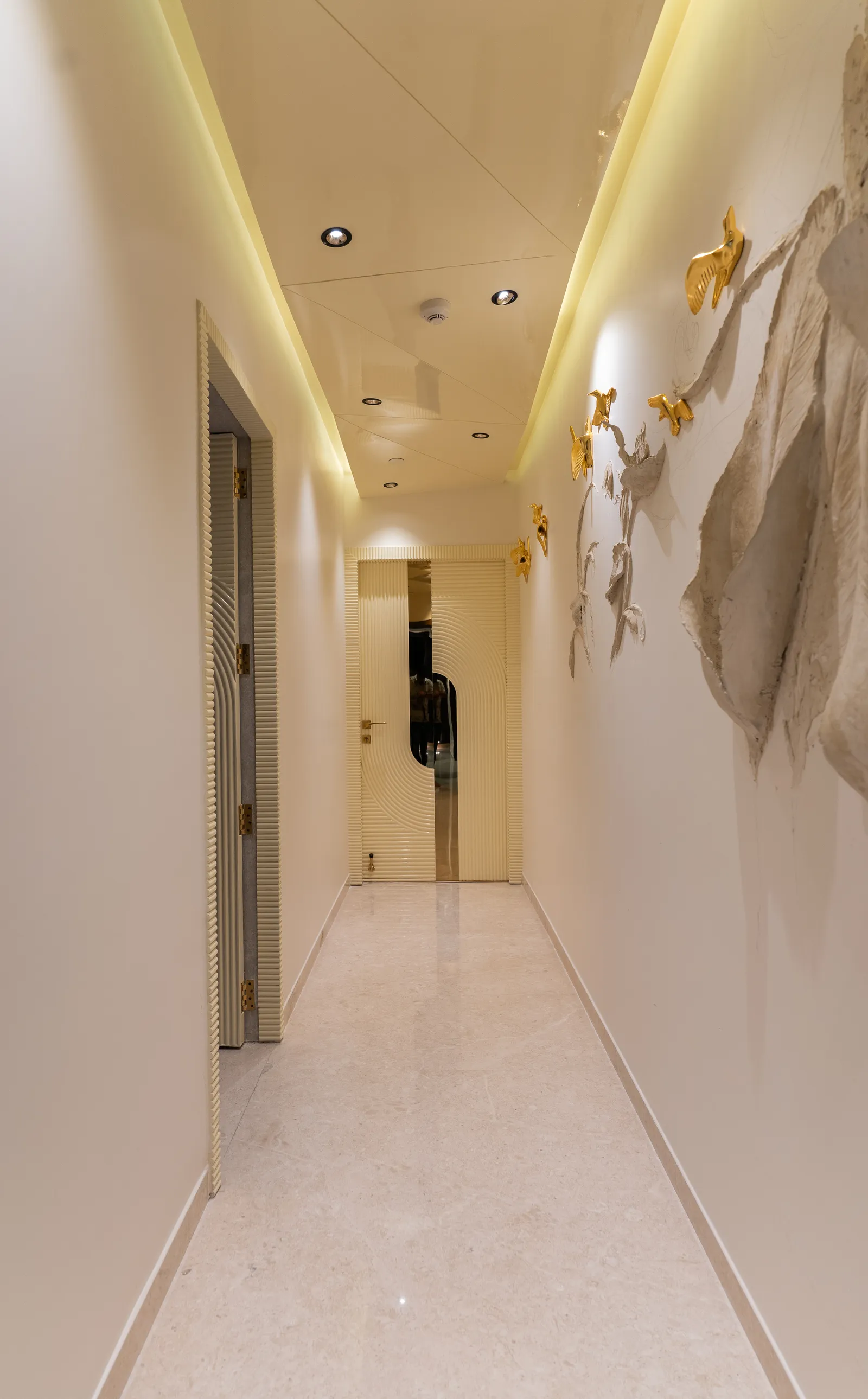 Corridor with cove lighting and sculptural wall decor — Abhishek's Residence
